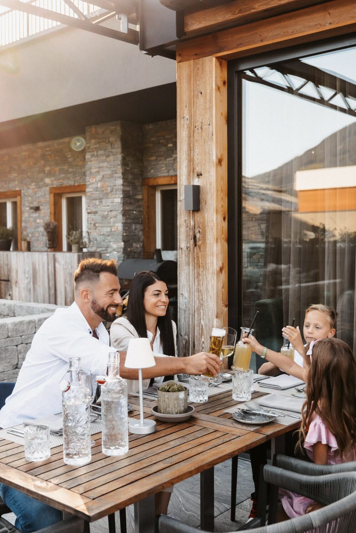 Familie genießt ein entspanntes Abendessen auf der Terrasse des Restaurant vaMoos im Hofgut Wagrain.