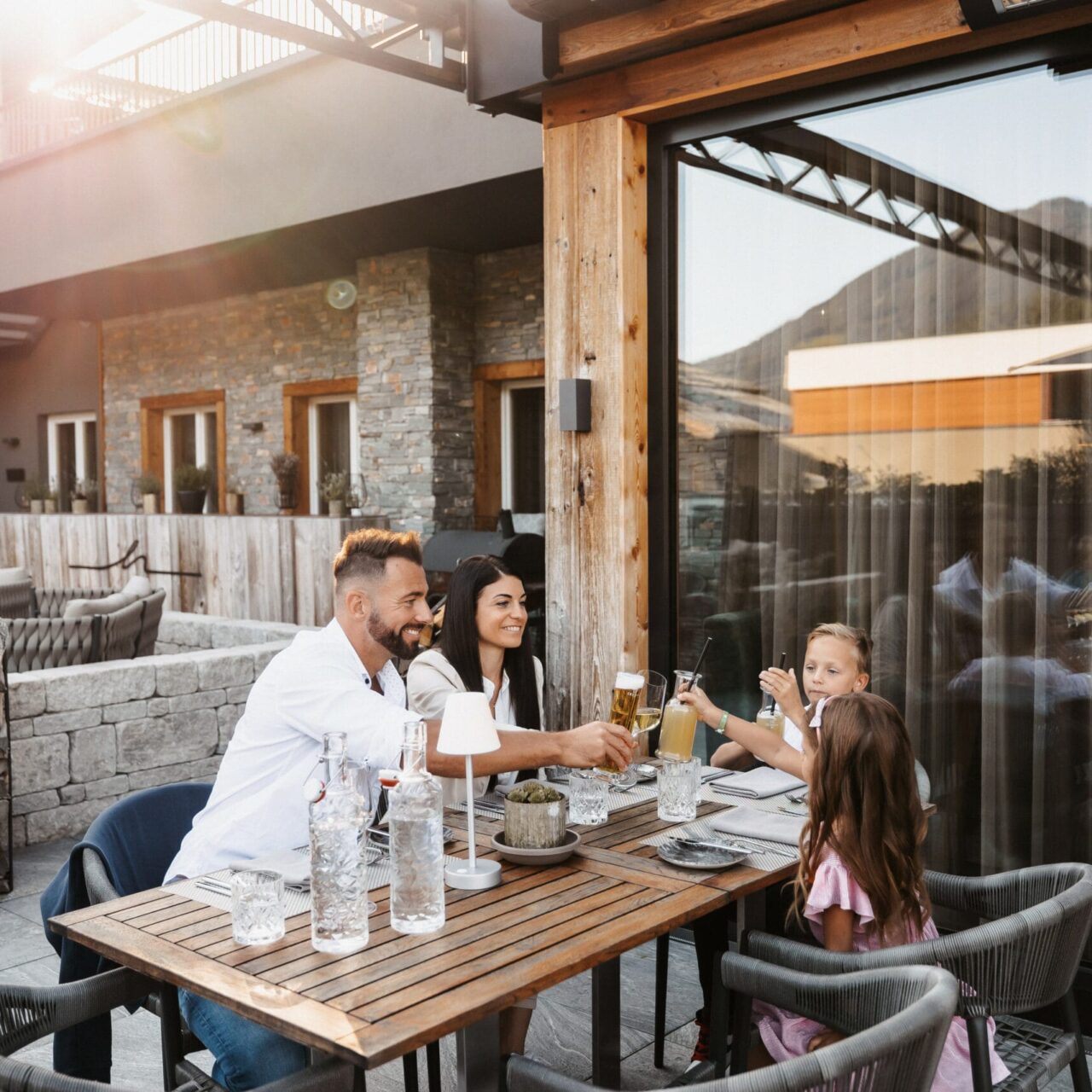 Familie genießt ein entspanntes Abendessen auf der Terrasse des Restaurant vaMoos im Hofgut Wagrain.