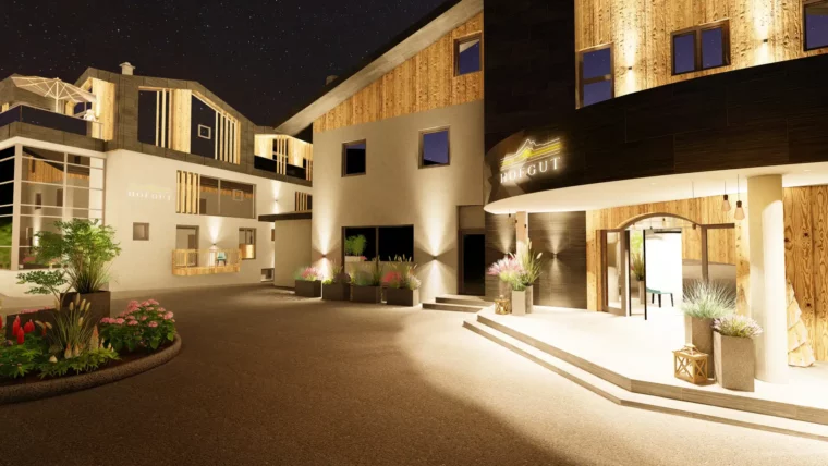 Atmospheric evening shot of Hofgut Wagrain - the invitingly illuminated hotel entrance with modern architecture, natural materials and lovingly planted plants promises warm hospitality and Alpine joie de vivre from the very first moment.