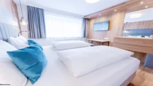 Helles Schlafzimmer mit modernem Holzdesign und kuscheligen Kissen im Hofgut Wagrain – alpiner Wohnkomfort für entspannte Familienurlaube.