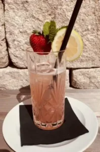 Summer indulgence at Hofgut Wagrain - fruity cocktail with strawberries, lemon and mint, served in a fine crystal glass on the sun terrace. Refreshing, stylish and full of Alpine flair.