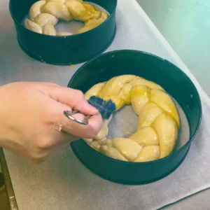 Hand-spread with love: A skilfully woven yeast dough wreath is finished with egg yolk before baking - baking tradition and craftsmanship in Hofgut style.