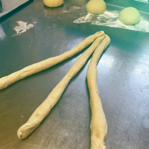 Three strands of dough are waiting to be woven into an Easter plait - lovingly handcrafted and in anticipation of a home-made treat at Hofgut Wagrain.