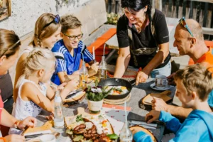 Fröhliche Familie genießt eine herzhafte Brettljause mit Spiegeleiern auf der sonnigen Almhütte – gelebte Gastfreundschaft und regionale Genussmomente im Salzburger Land.