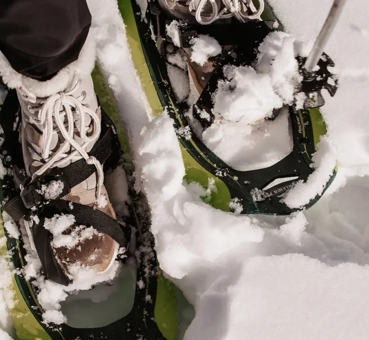 Schneeschuhwanderung im Tiefschnee – Nahaufnahme von zwei Füßen in Schneeschuhen auf frischem, unberührtem Pulverschnee.