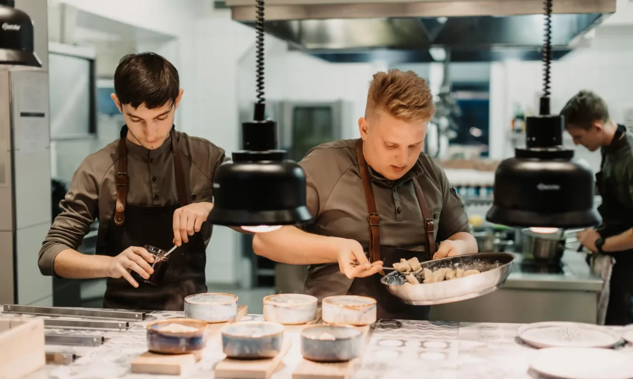 Chefs preparing and preparing food in an open, modern hotel kitchen - focus on teamwork and culinary precision.