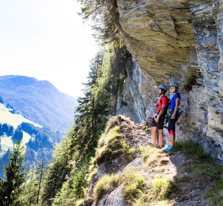 To vandrere på en via ferrata med udsigt over bjergene