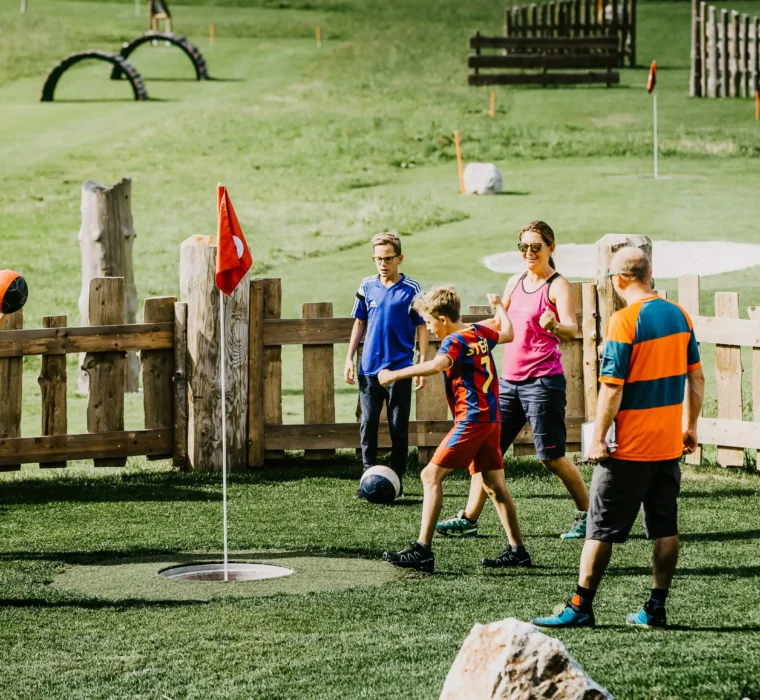 Fun, games and team spirit - families experience active summer moments full of joy while playing football golf together in the countryside.