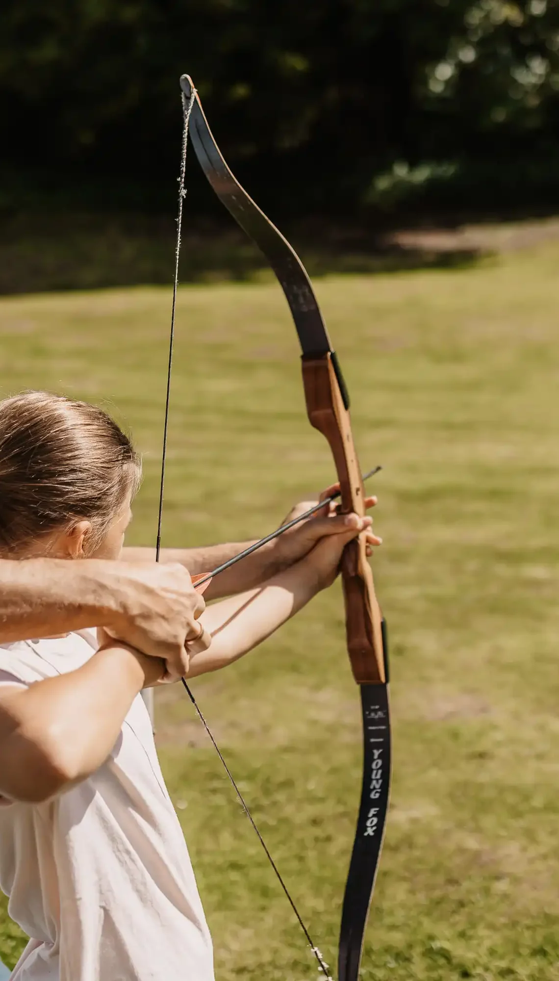 Zielsicher im Urlaub – gemeinsames Bogenschießen für Kinder und Erwachsene auf der Wiese bei Sonnenschein.