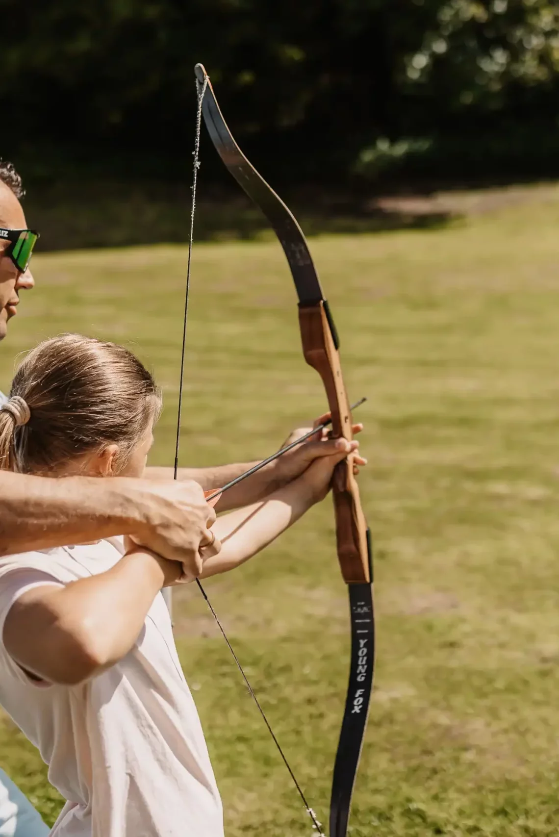 Zielsicher im Urlaub – gemeinsames Bogenschießen für Kinder und Erwachsene auf der Wiese bei Sonnenschein.