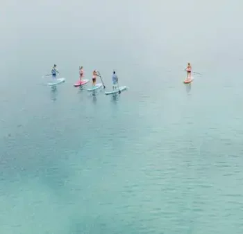 Stand-up paddling on turquoise blue water - a shared nature experience full of lightness and summer fun.