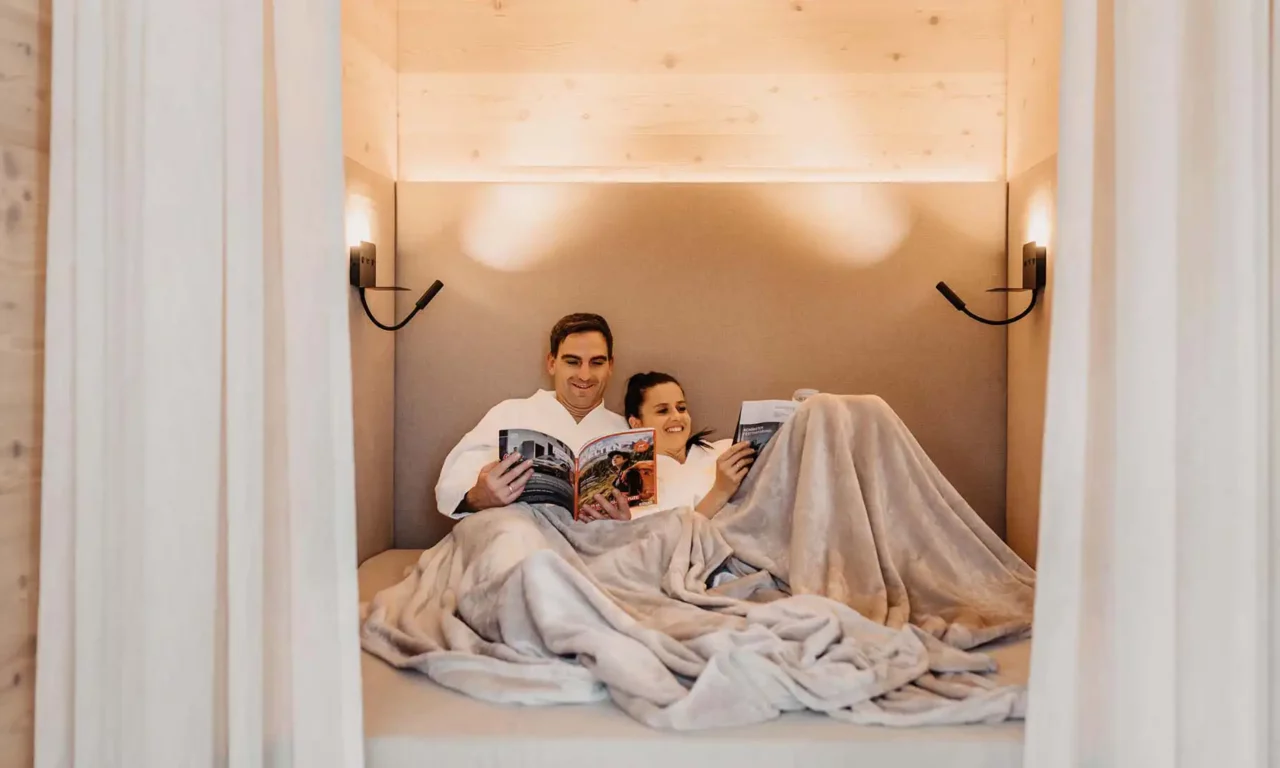 Feel-good time together - snuggled up reading and relaxing in the stylish retreat of the adults-only wellness area at Hofgut Wagrain.