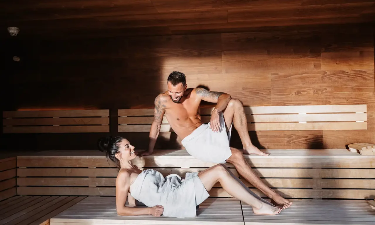 Man en vrouw genieten van de warmte van een stijlvolle houten sauna.