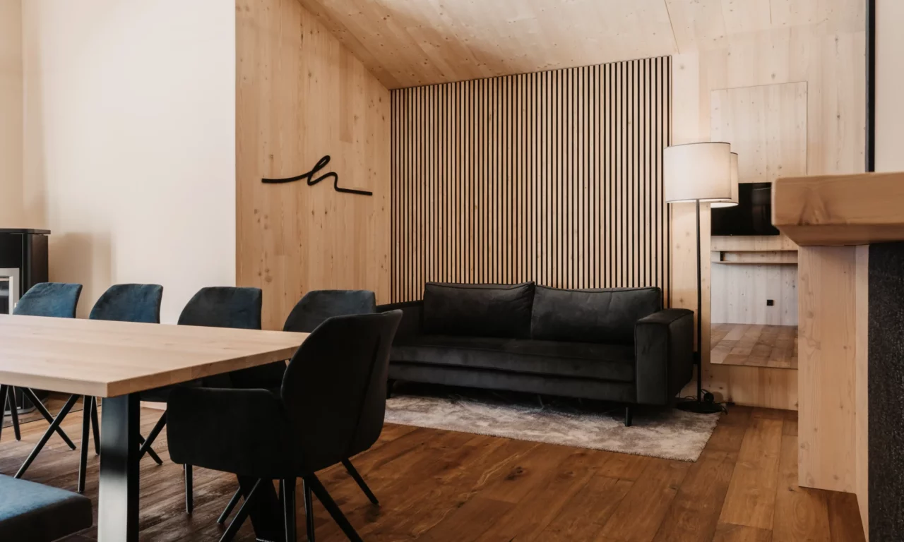 Cosy living area at Hofgut Wagrain: elegant sofa in front of stylish wood panelling, warm lighting accents and modern interior for relaxed family moments in an alpine ambience.