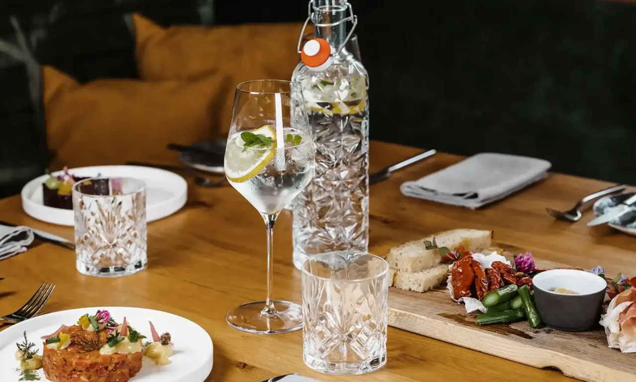 Gedeckter Tisch mit Wasserflasche, Getränk und Speisen im Restaurant.