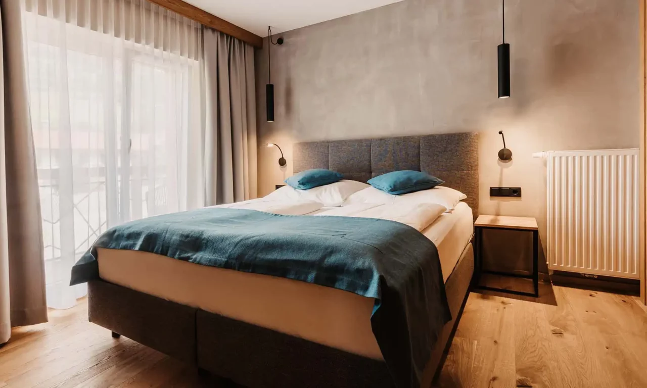 Modern eingerichtetes Schlafzimmer mit Doppelbett und Holzfußboden im Apartment des Hofgut Wagrain