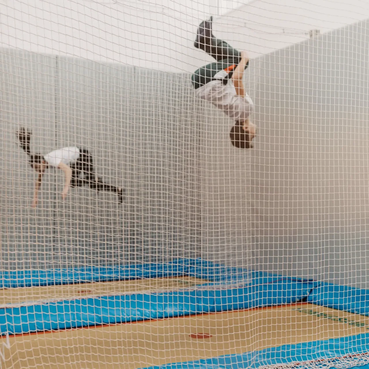 Zwei Kinder springen auf Indoor-Trampolinen im Hofgut Wagrain, gesichert durch ein Netz.