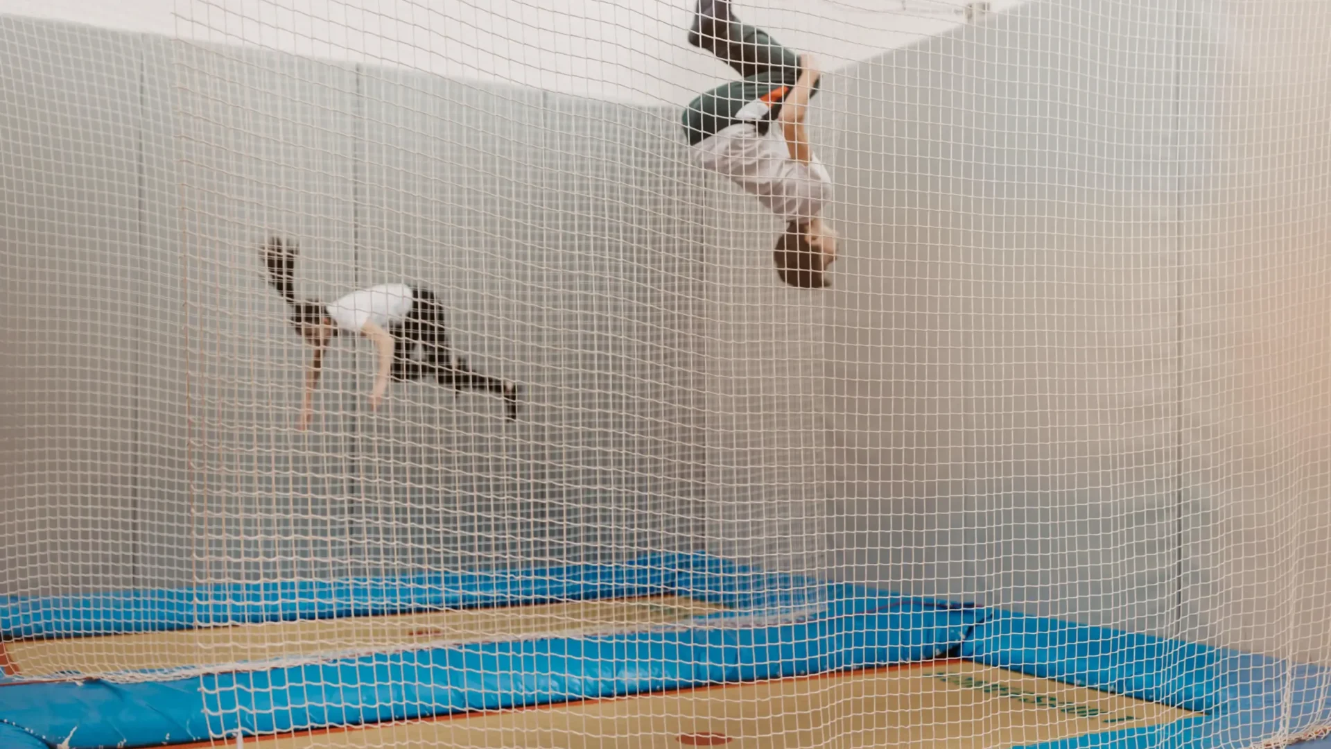Zwei Kinder springen auf Indoor-Trampolinen im Hofgut Wagrain, gesichert durch ein Netz.