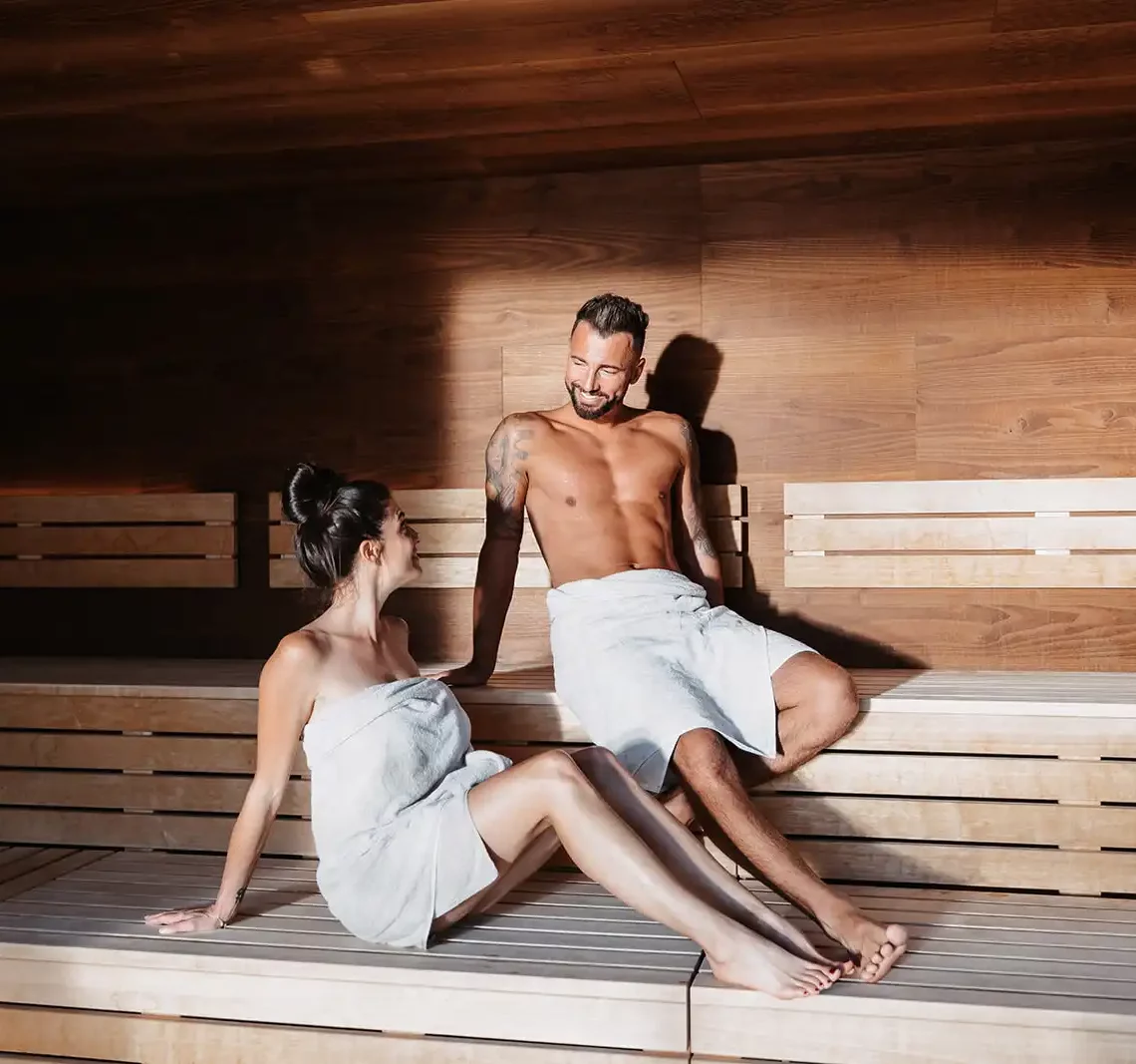 Een ontspannen stel geniet van de warmte van de panorama sauna in Hofgut Wagrain.