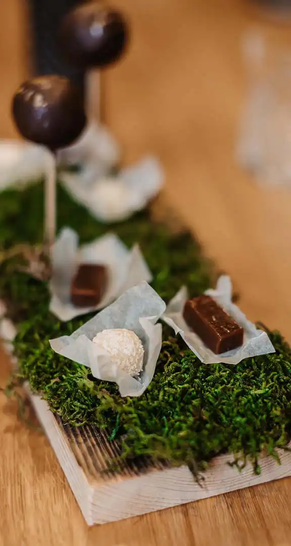 Homemade pralines and chocolate lollipops on a bed of moss – artfully arranged at the vaMoos Restaurant in Hofgut Wagrain.