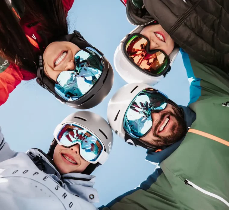 Familie blickt beim Skifahren mit Skihelm in die Kamera