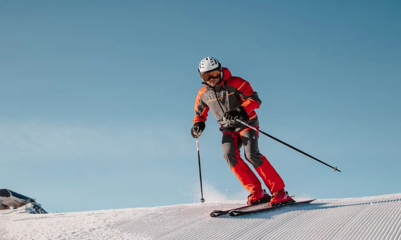 Skiër in een rood skipak maakt bochten op perfect geprepareerde pistes in Ski Amadè.