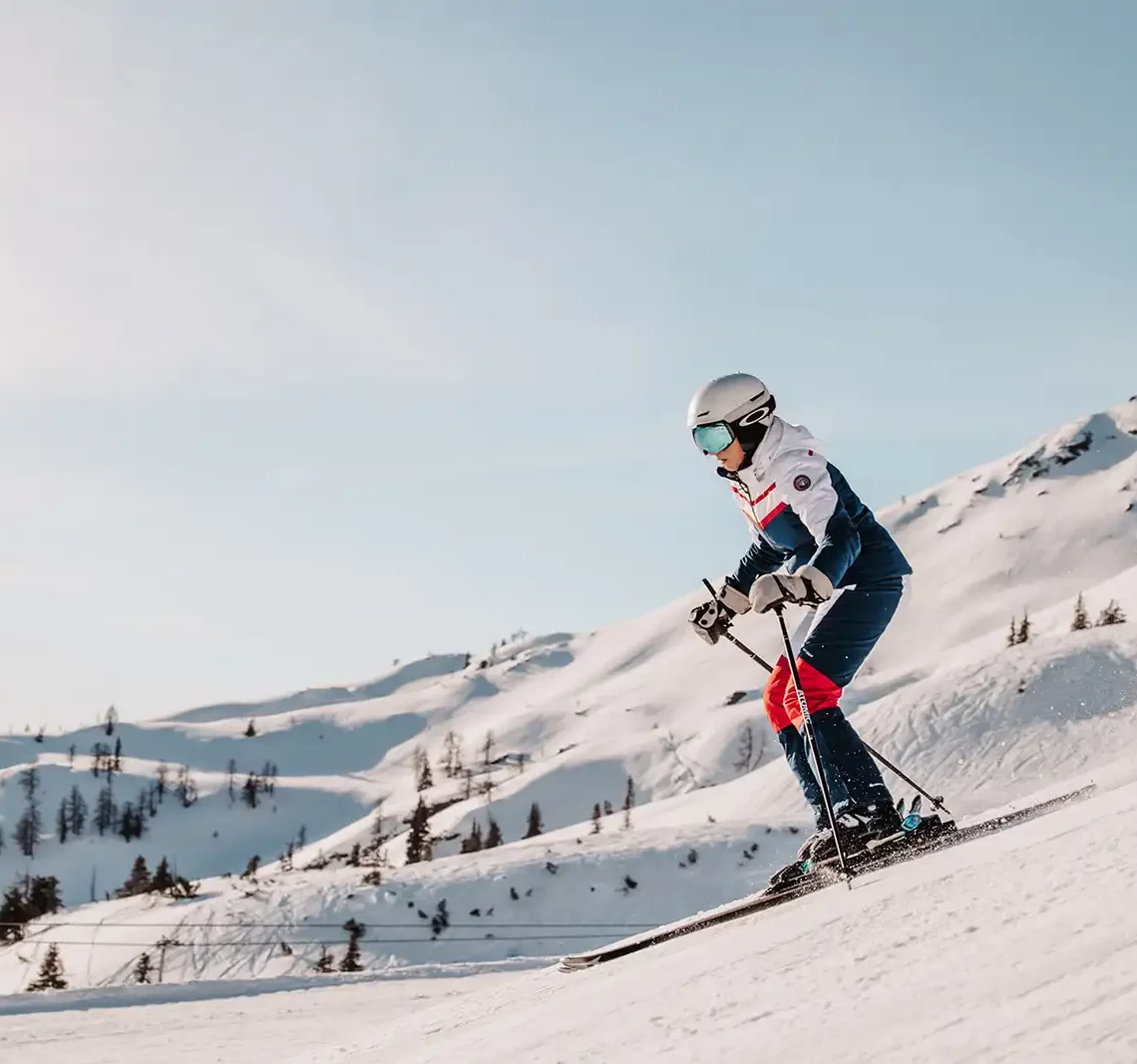 Skifahrerin fährt bei strahlenden Sonnenschein die Skipisten in Ski Amadè.