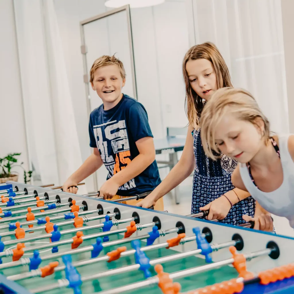 05.HOFGUT-apartment-lifestyle-resort-apartment-kicker-wuzzler Children play table soccer at Hofgut Wagrain.