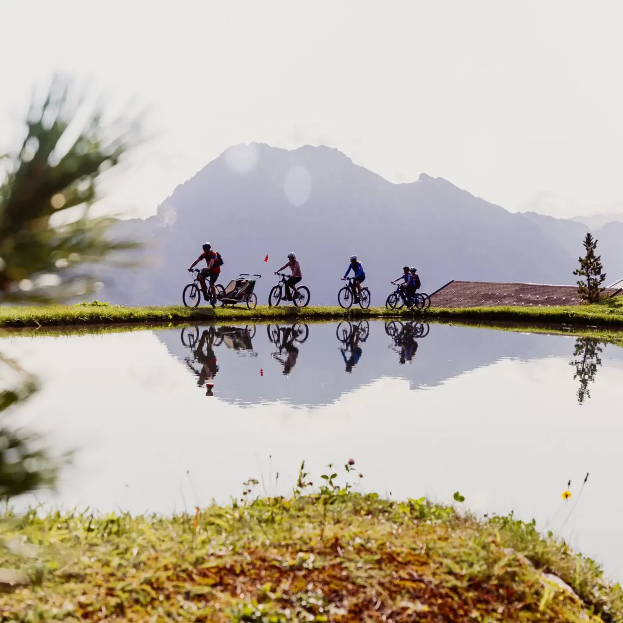 Family e-biking along a mountain lake with a reflection and Alpine panorama in Salzburger Land