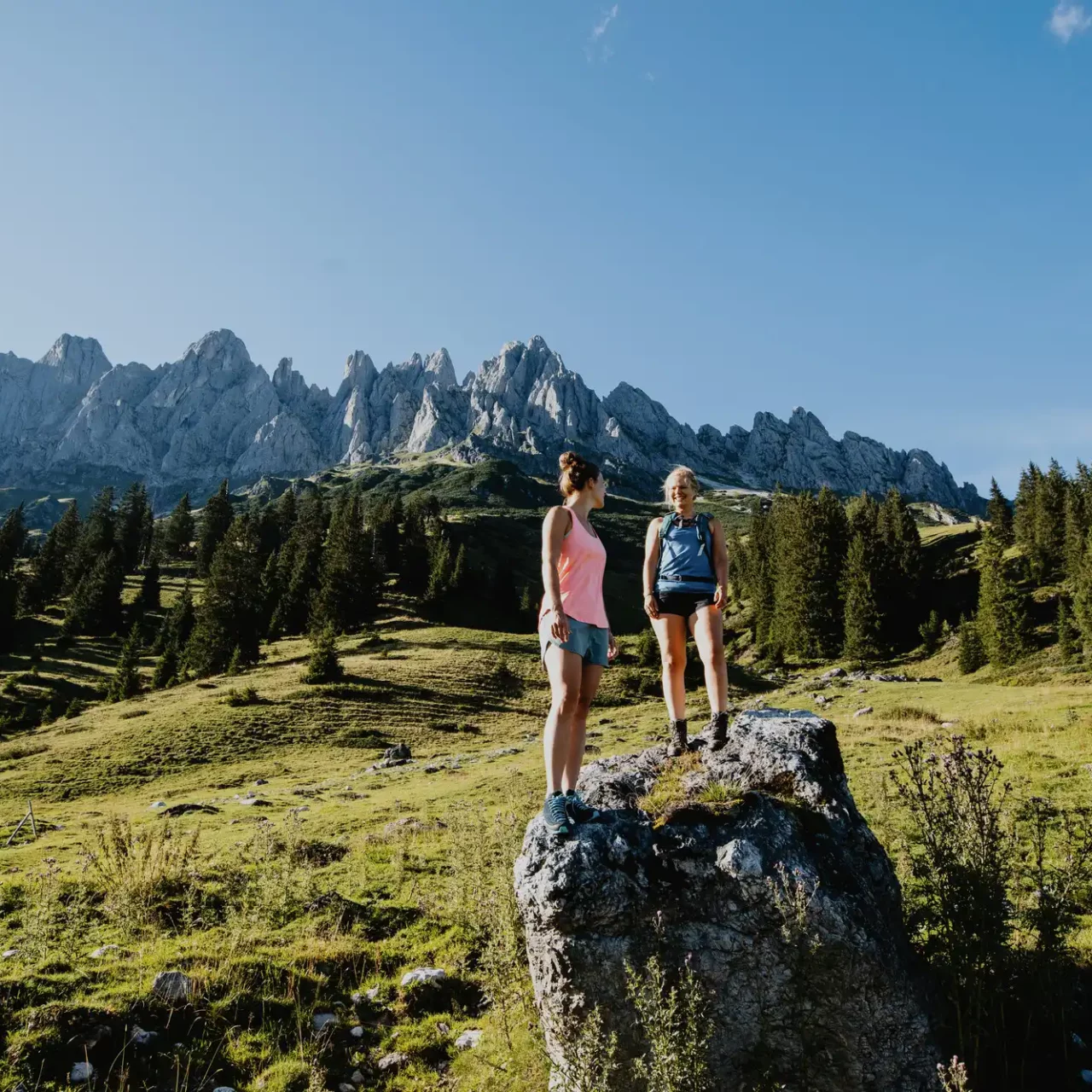 Two women hiking in Salzburger Land with a view of the striking peaks of the Tennengebirge mountains