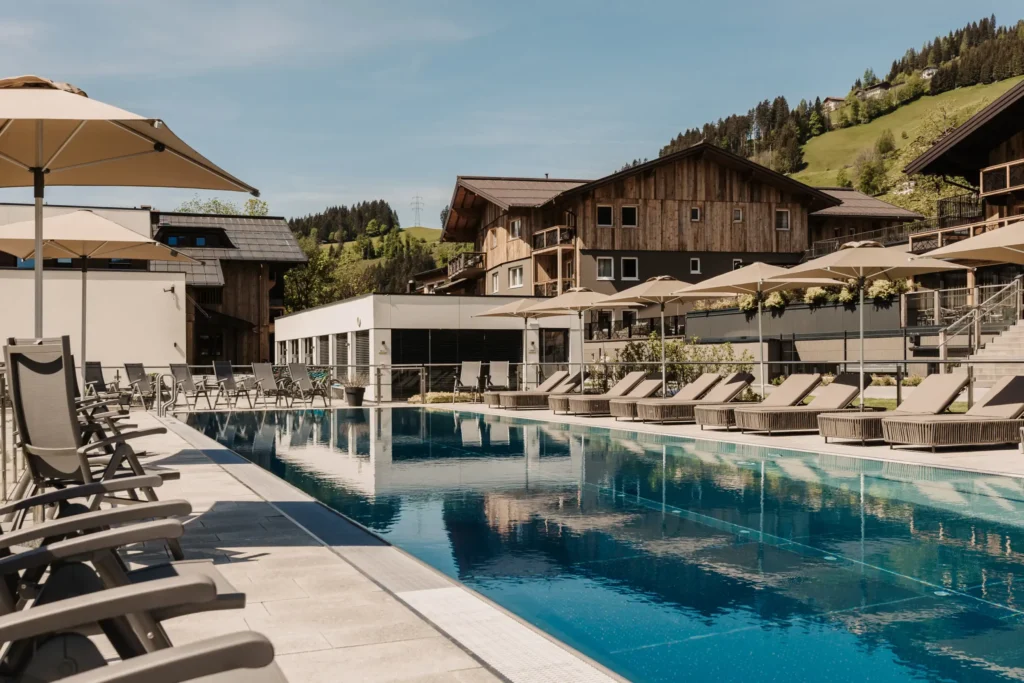 25-metre sports pool at Hofgut Wagrain with loungers and umbrellas - summer oasis of peace with mountain views for active and relaxing holidays in Salzburger Land.