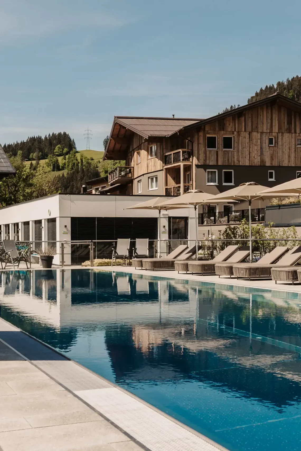 25-Meter-Sportbecken im Hofgut Wagrain mit Sonnenliegen und Schirmen – Sommerliche Ruheoase mit Bergblick für aktive und entspannte Urlaubstage im Salzburger Land.
