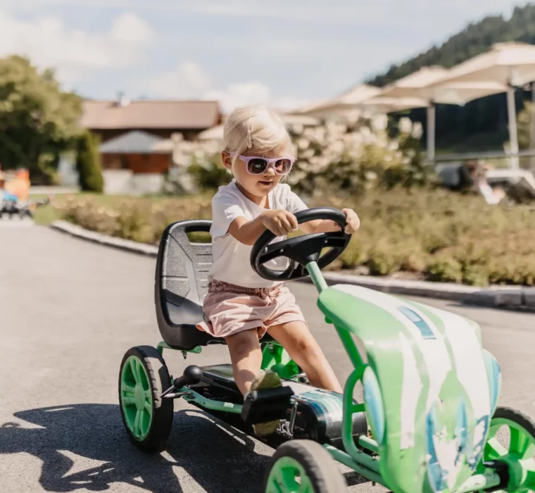 Kinder fahren mit Gokarts und Laufrädern durch das Hofgut Wagrain