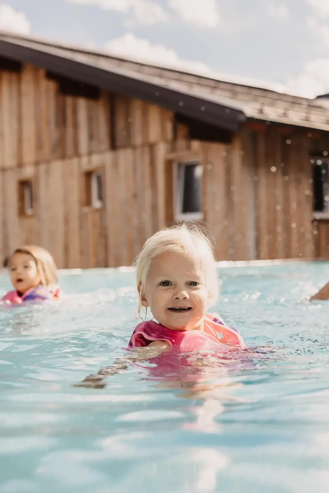 Kleines Kind mit Schwimmhilfe im Outdoorpool des Hofgut Wagrain beim Baden mit der Familie
