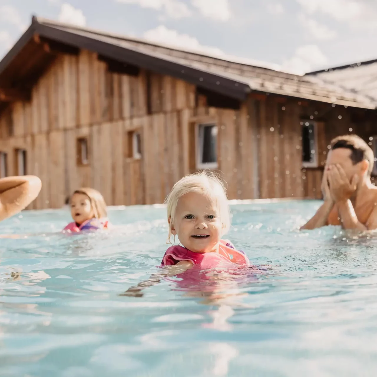 Hofgut-Wagrain-Apartment-Resort-Wagrain 602 Small child with swimming aid in the outdoor pool at Hofgut Wagrain swimming with the family