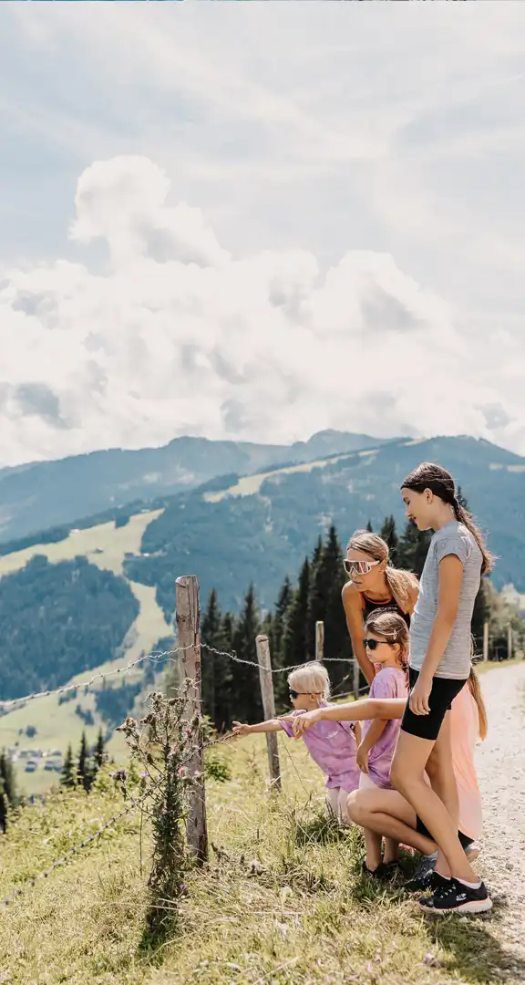 Mutter wandert mit ihren drei Kindern auf einem Panoramaweg in den Bergen rund um das Hofgut Wagrain – gemeinsames Naturerlebnis mit Blick auf die alpine Landschaft.