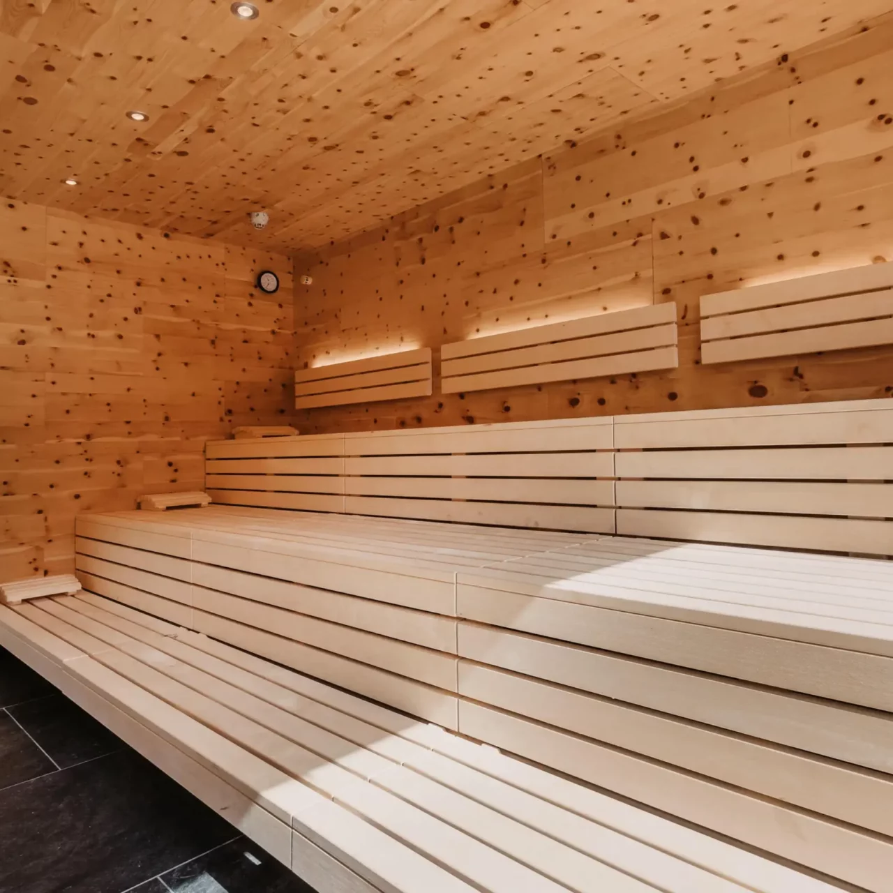 Lys schweizisk fyrretræssauna på Hofgut Wagrain - beroligende varme, velduftende schweizisk fyrretræ og moderne design til afslappende øjeblikke af velvære i wellnessområdet kun for voksne.