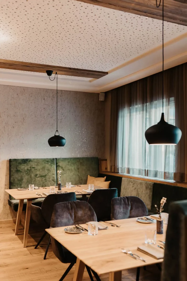 Gemütlicher Restaurantbereich im Hofgut Wagrain mit stilvoller Einrichtung, weichen Polstern und liebevoll gedeckten Tischen – alpine Wohlfühlatmosphäre zum Genießen.