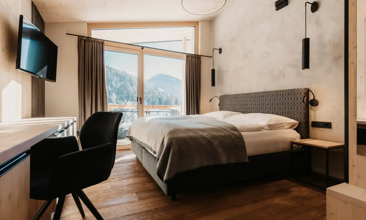 Alpine charm combines with modern design: a cosy bedroom with panoramic views and stylish details.