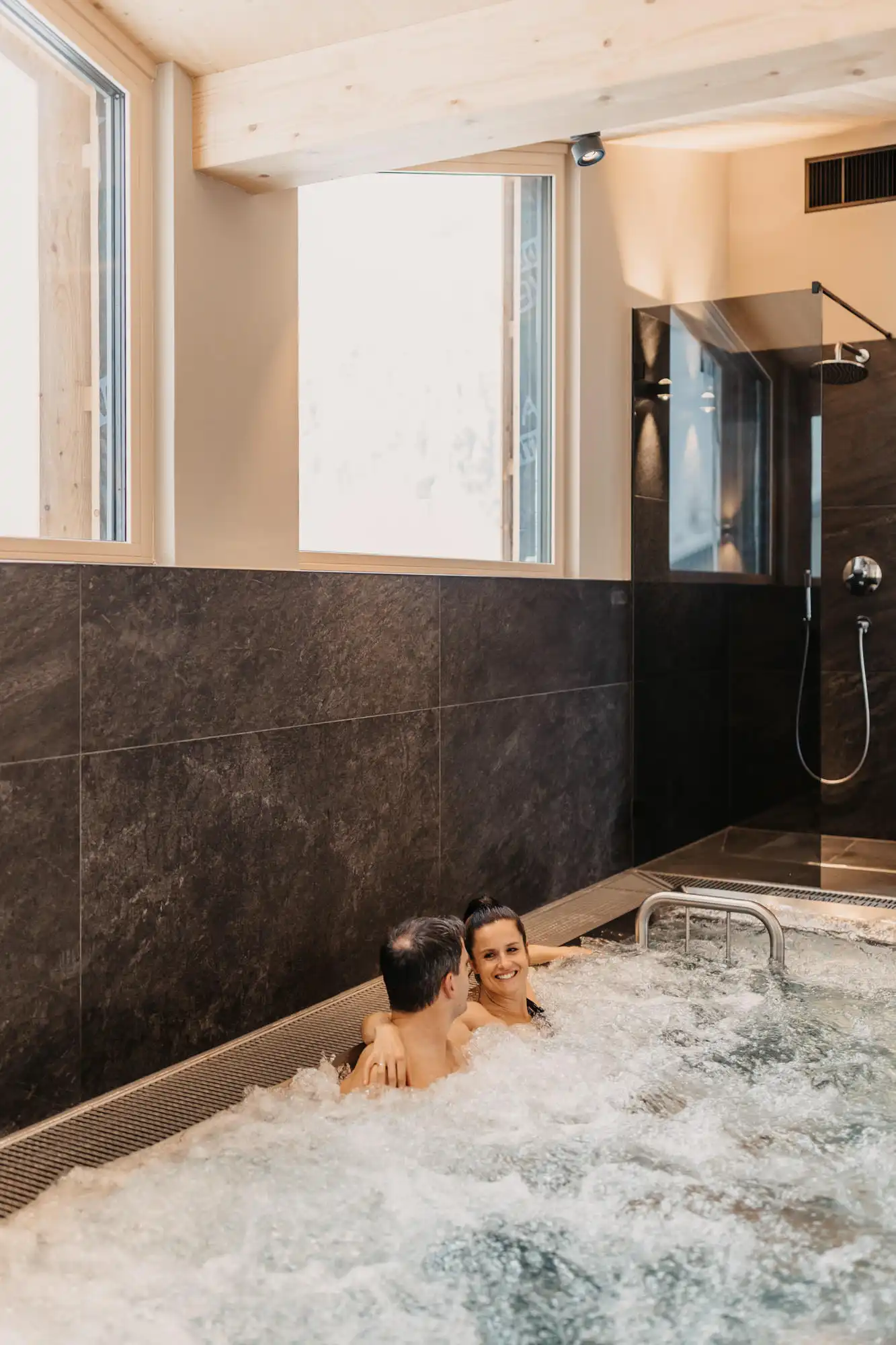 Hofgut-wagrain-apartment-280 A couple relax in the bubbling whirlpool with eye contact - a pure feel-good moment.