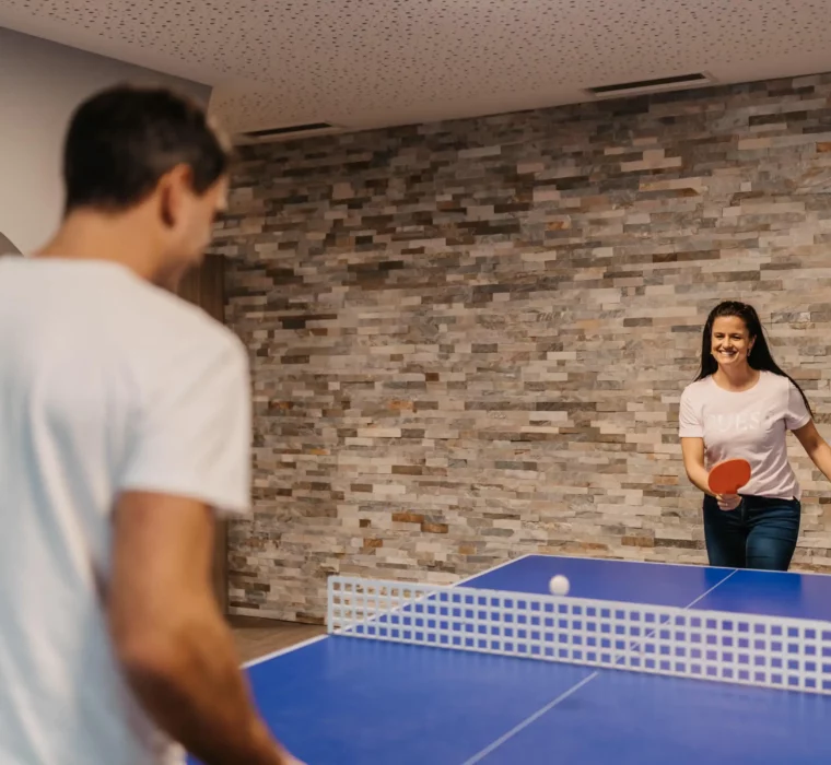 Sporty fun on holiday: a table tennis duel with lots of laughter and exercise - active time for couples at Hofgut Wagrain.