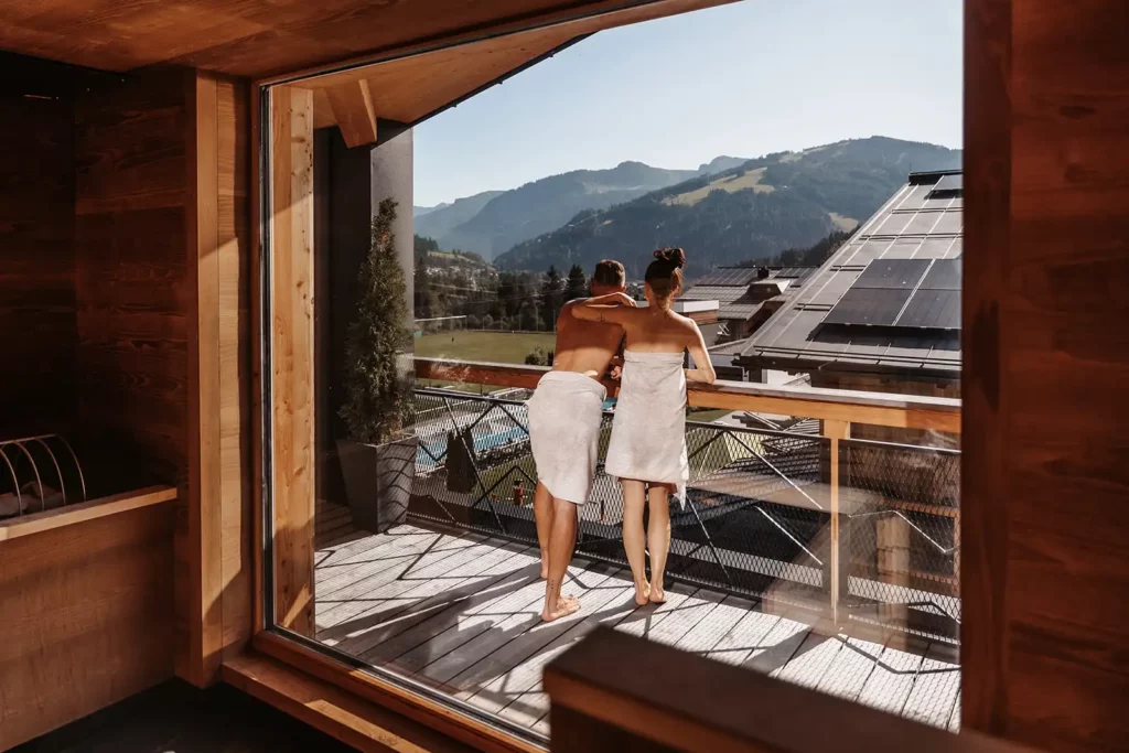 Hofgut©Elisabeth_Fotografie-Saunabereich_618 Togetherness with a view - a couple enjoys the panoramic view of the Alps from the relaxation area of the ski sauna at Hofgut Wagrain. Warm wood tones, fresh mountain air and soothing relaxation combine to create a special feel-good moment.