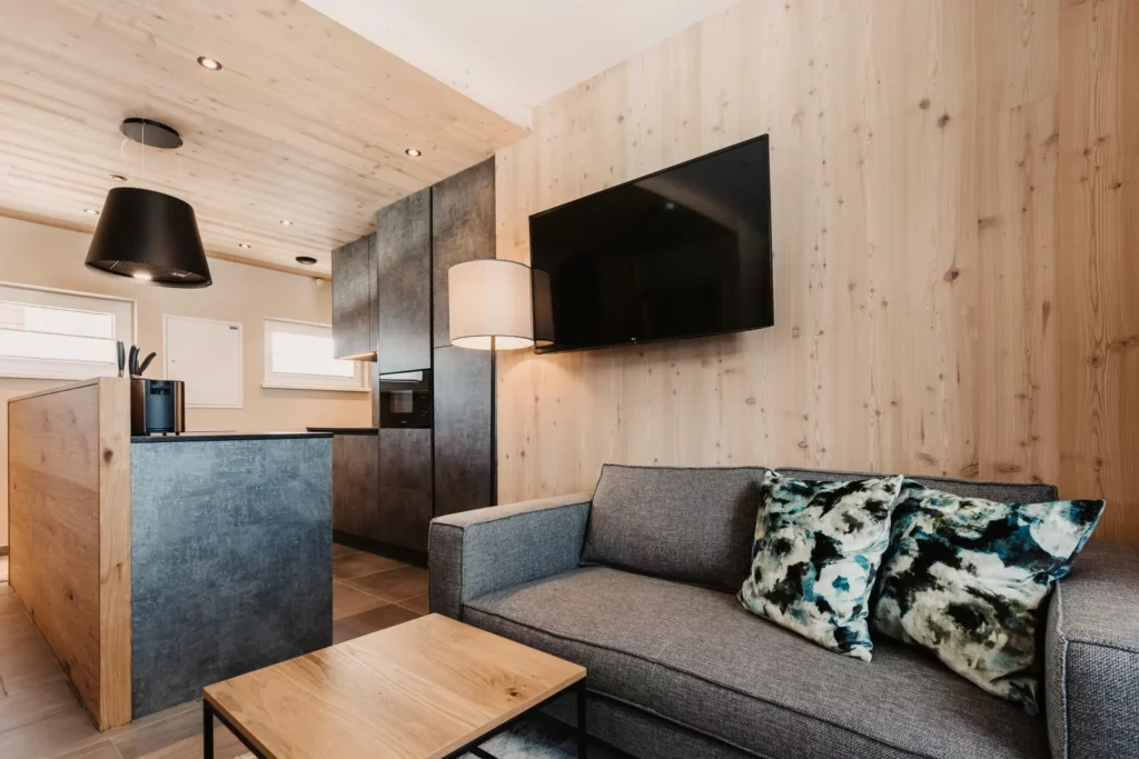 Living area with sofa, coffee table and open-plan kitchen in the Lärche flat at Hofgut Wagrain.