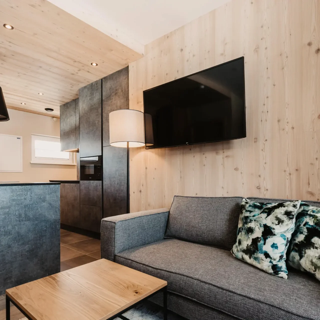 Wohnbereich mit Sofa, Couchtisch und offener Küche im Apartment Lärche im Hofgut Wagrain.