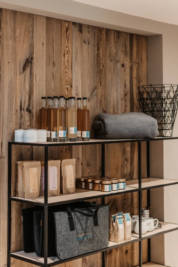 hofgut-apartment-lifestyle-resort-shop-rezeption Shelf in the Hofgut shop with regional products: Syrup, tea, honey, candles and accessories in alpine style.