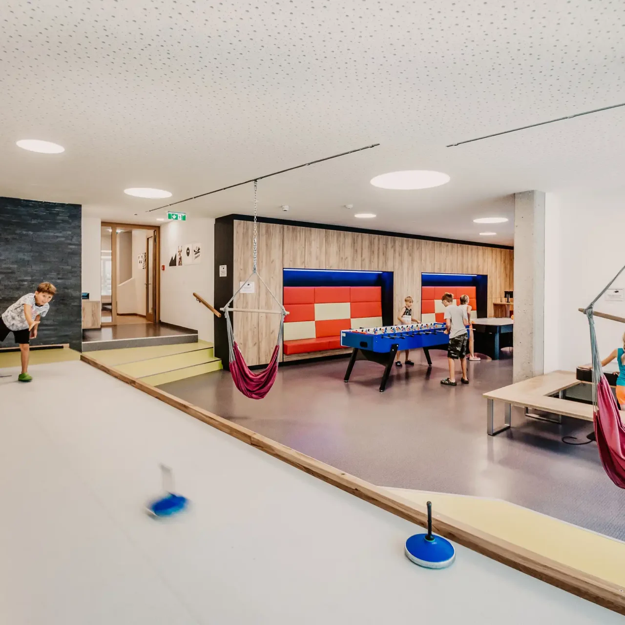 Moderne Indoor-Spielewelt im Hofgut Wagrain mit Kegelbahn, Tischfußball, Hängesesseln und Spieltischen – ideal für Kinder und Familienurlaub in Österreich