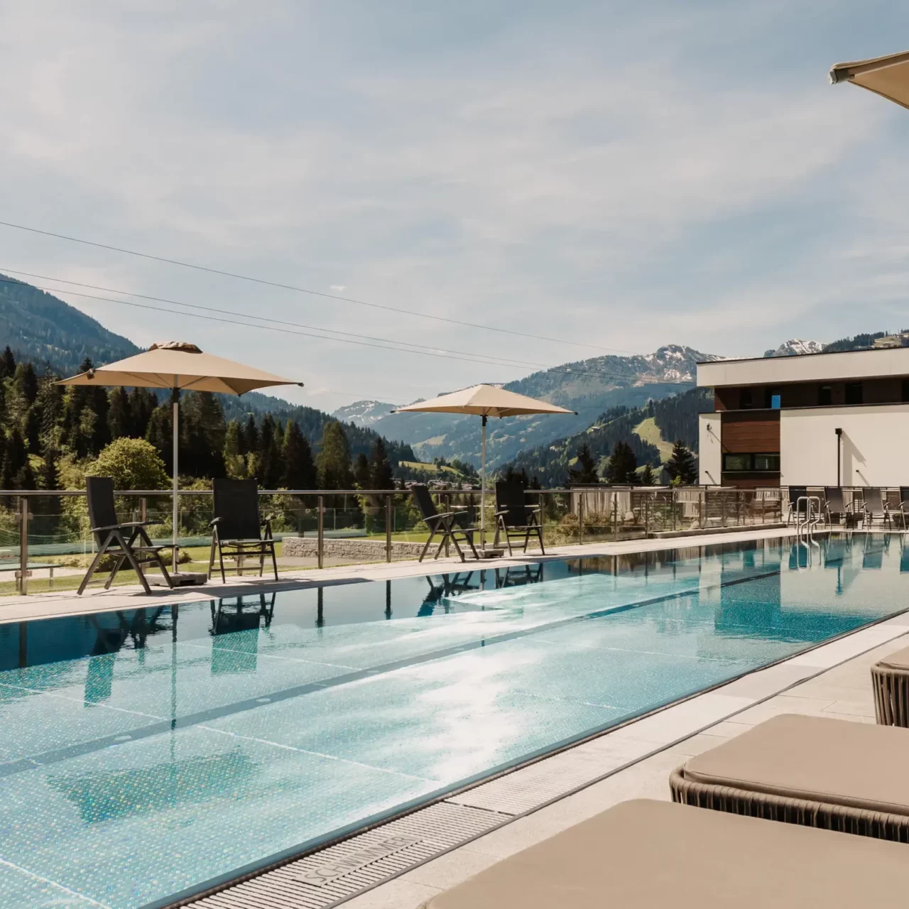 25-metre sports pool at Hofgut Wagrain with sun loungers and umbrellas - summer oasis of peace with mountain views for active and relaxing holidays in Salzburger Land.
