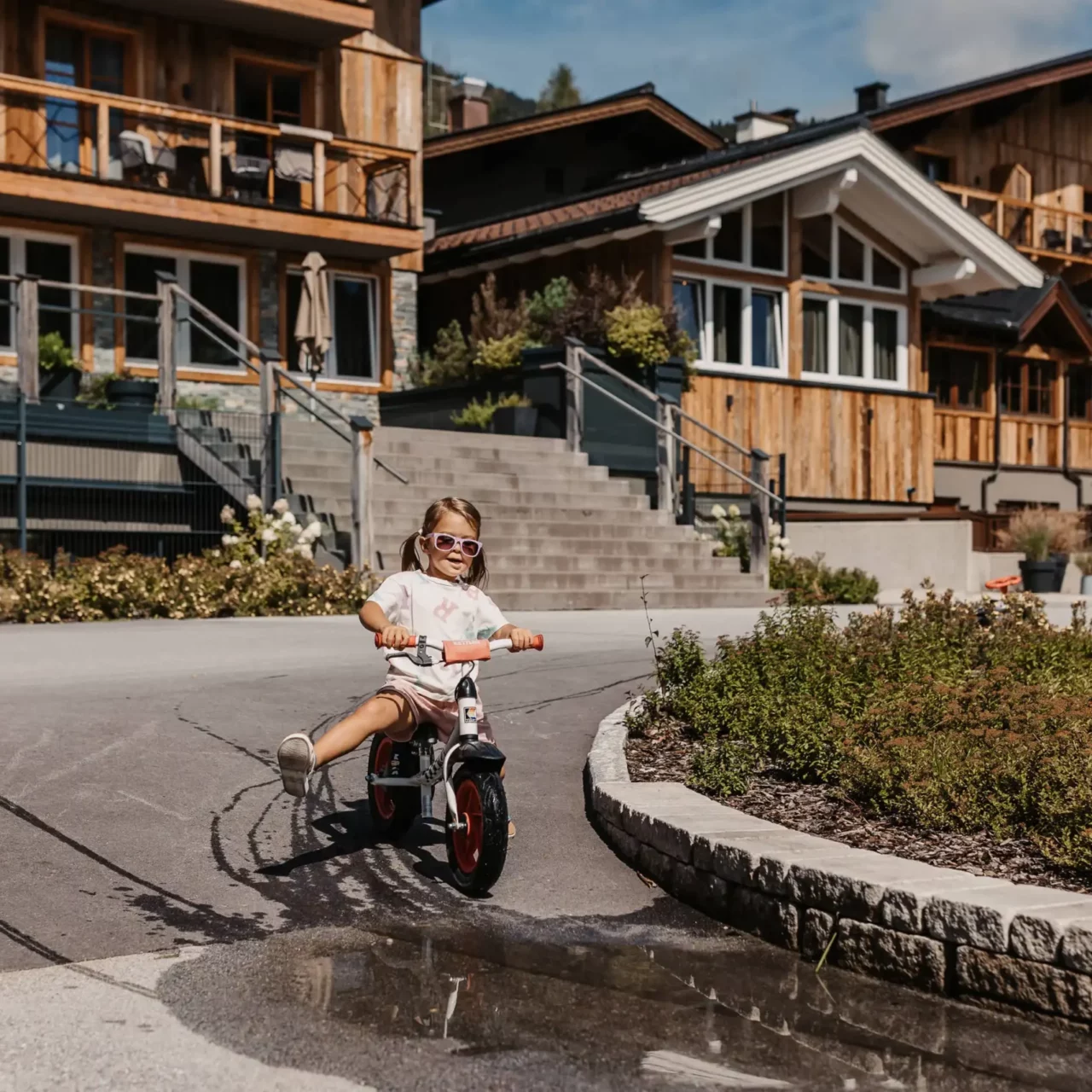 Kind mit Laufrad unterwegs am Poolbereich des Hofgut Wagrain