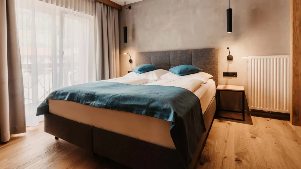 Hofgut-Wagrain-Apartment-Resort-Wagrain-Schlafraum-Eiche7- 427 Gemütliches Doppelzimmer mit Boxspringbett, Holzboden und stilvollem Lichtkonzept im alpinen Design