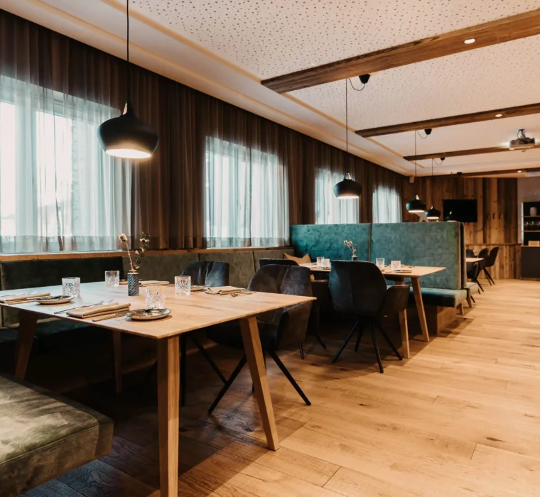 Cosy restaurant atmosphere at Hofgut Wagrain with a stylish wooden look, elegant tableware and inviting bench seating - moments of enjoyment for the whole family in an Alpine lifestyle ambience.